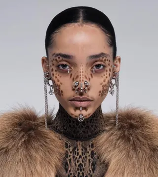 Portrait of female middle eastern AI model with silver piercings in nose area, ears and chin. Face covered by brown animal pattern face paint. Fur coat. AI fashion editorial.